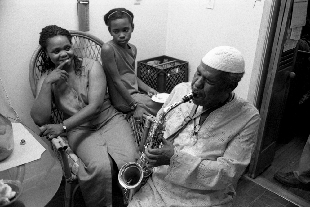 a man playing saxophone while a woman and child are listening