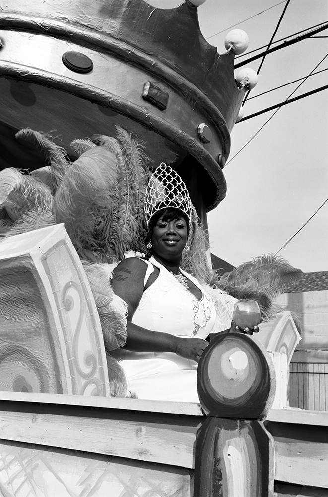 a costumed woman sitting on a car during the parade