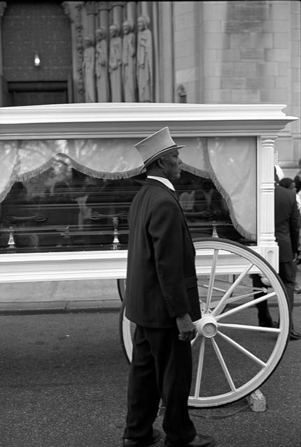 a man in a top hat next to a casket